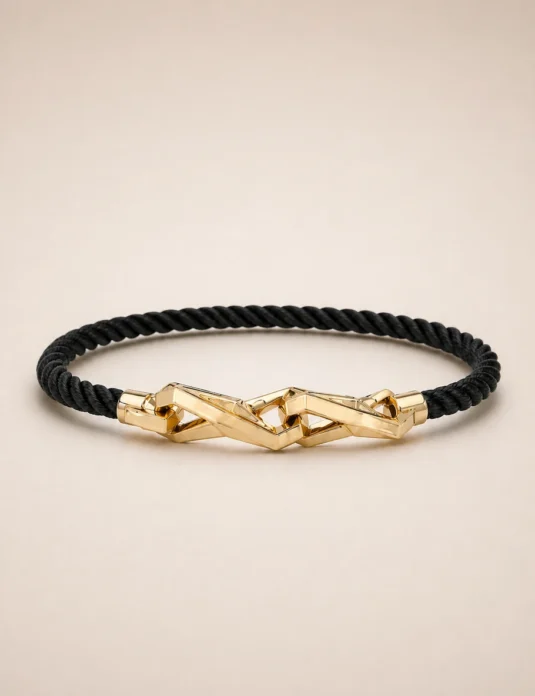 Bracelet en cordon noir doré avec fermoir géométrique en or 18 carats sur fond beige