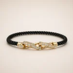 Bracciale in oro 18 carati con cordino in diamanti, cordino nero intrecciato e diamante centrale geometrico su sfondo neutro