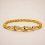 Pulsera de cuerda trenzada dorada con cierre de cadena entrelazada geométrica en el centro.