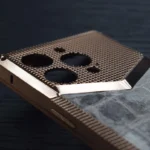 Rose gold titanium iphone case with honeycomb mesh pattern and marble back panel on dark surface