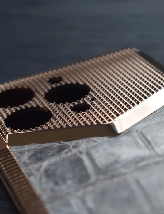 Rose gold titanium iphone case with 24k gold plating and geometric mesh pattern on marble surface