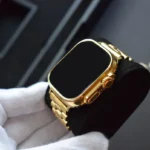 Apple Watch Ultra 2 en or 24 carats avec boîtier et bracelet en or poli miroir, tenue par des mains gantées de blanc