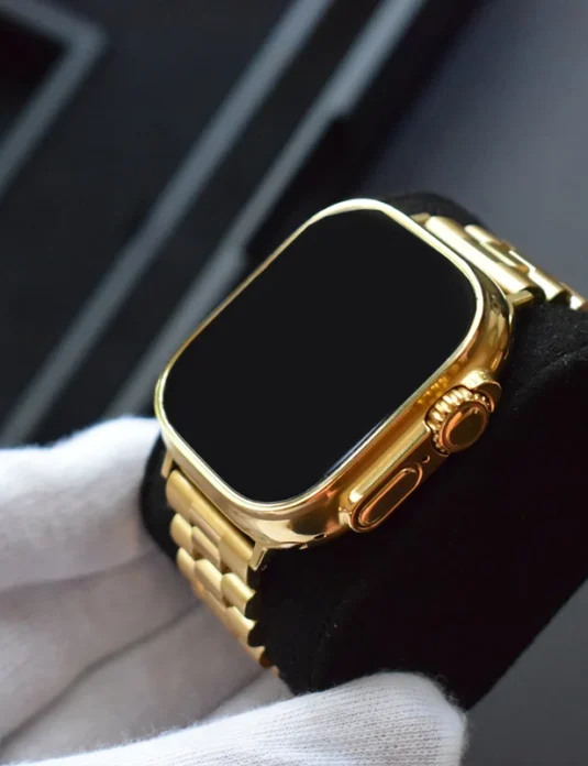 Apple Watch Ultra 2 de oro de 24 quilates con caja y brazalete de oro pulido a espejo, sostenido por manos enguantadas de blanco
