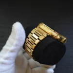Goldene Apple Watch Ultra mit individueller Gravur und kunstvollen Mustern auf Gehäuse und Armband, gehalten in weißen Handschuhen