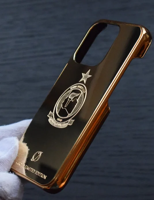 24k gold iPhone case custom logo with golden bumper frame and personalized emblem engraving held in white gloved hands