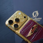 هاتف آيفون 17 برو منقوش بنقش جلد التمساح الذهبي، مع ظهر من الجلد العنابي ونقوش باروكية