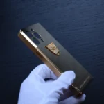 金色钛金属iPhone手机壳，饰有黑豹图案，由白手套托举，尽显奢华的24K镀金工艺。