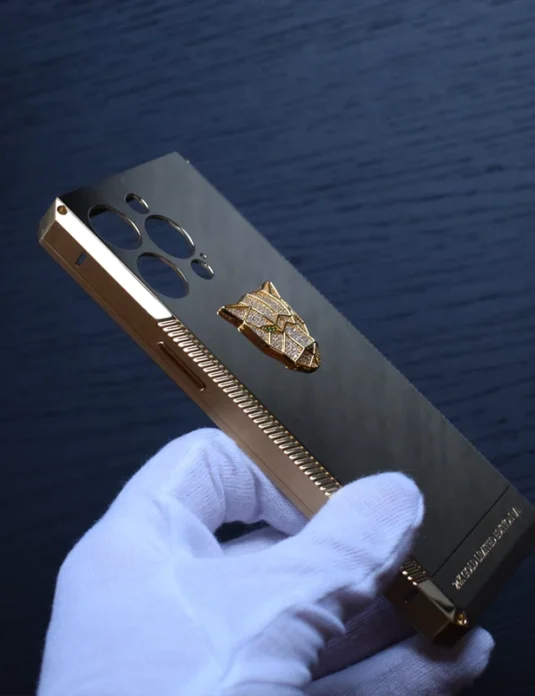 Gold titanium iphone case with panther emblem held in white gloves showing luxurious 24k gold plating
