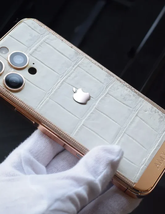 Rose gold iPhone 16 Pro Max crocodile leather with white Himalayan texture and Swarovski crystals held in gloved hands