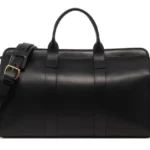 Black leather duffle bag with dual handles and shoulder strap on white background