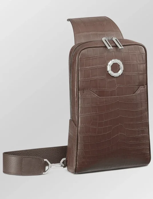 棕色鳄鱼皮斜挎包，采用纹理皮革饰面，配有可调节肩带，图中为正面视角。