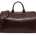 棕色皮革旅行包，结构挺括，配有双提手和可调节肩带