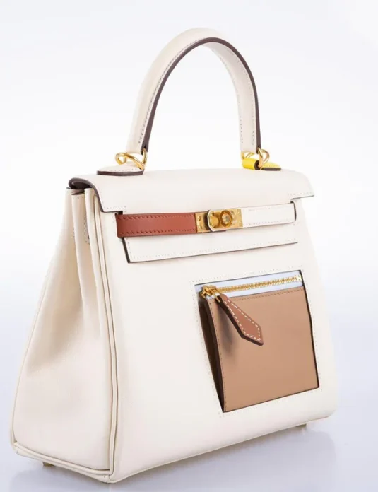 白色皮革凯莉手提包，饰以棕色点缀和金色五金配件，展现出挺括的造型和正面口袋细节。