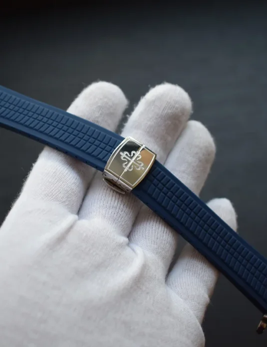Blue rubber apple watch bands with textured pattern and gold hardware held in white gloved hand