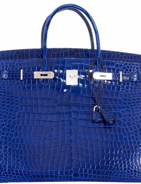这款蓝色鳄鱼皮手提包展现了光泽亮丽的鳄鱼皮纹理，并搭配钯金配件。