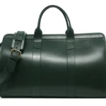 白色背景上的绿色皮革旅行包，配有黄铜五金件和肩带