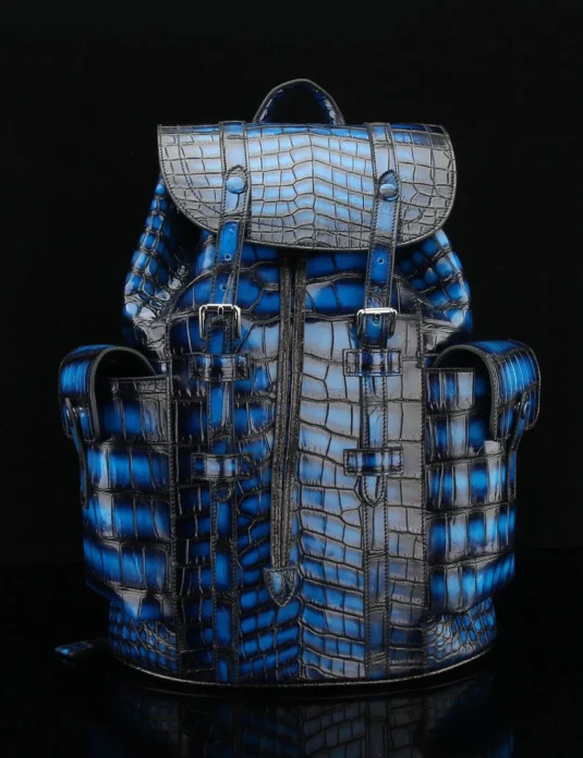 Blue crocodile leather backpack with multiple compartments and buckle closures against black background