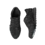 Black crocodile leather sneakers with monk strap buckles showing textured nubuck finish and rubber sole