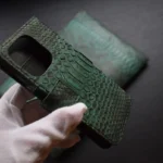 Green python leather flip phone case with scales texture and card slots shown in hands
