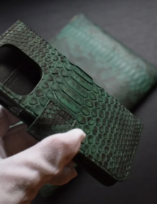 Green python leather flip phone case with scales texture and card slots shown in hands