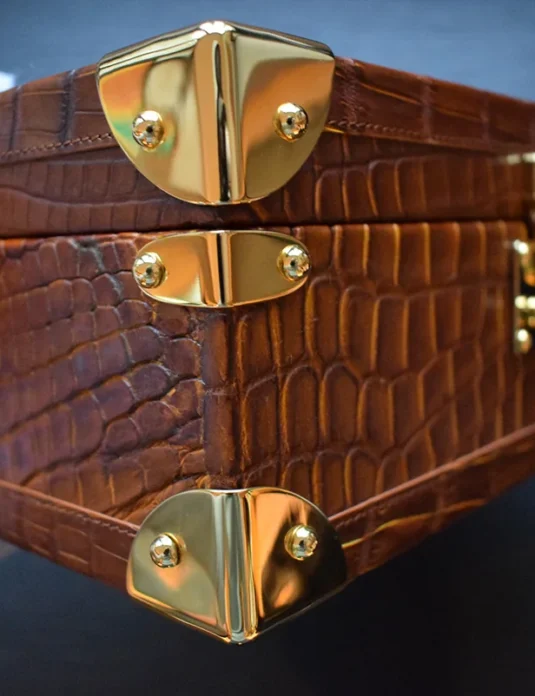 Braune Uhrenbox aus Krokodilleder mit goldfarbenen Beschlägen, die die Patina des Leders und die Innenfächer aus Wildleder zeigt