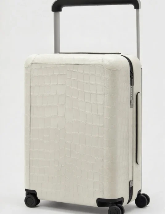 Maleta de piel de cocodrilo blanca con asa telescópica que muestra un patrón de escamas texturizadas y diseño con ruedas