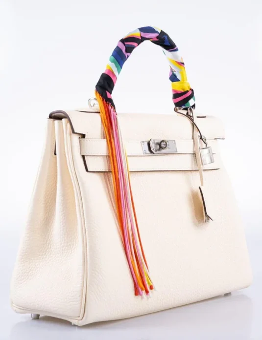 白色 Togo 皮革 Kelly 款手提包，搭配彩色丝巾和皮革流苏