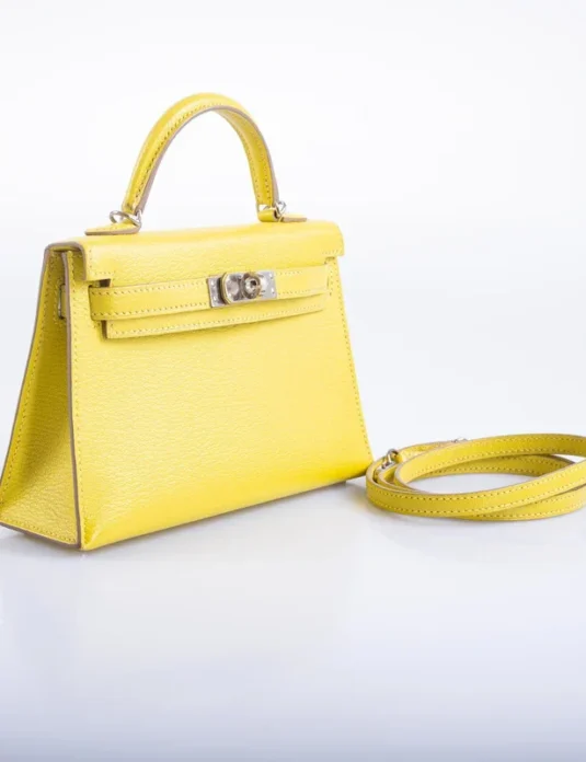 白色背景上的黄色皮革迷你手提包，凯莉款式，配有顶部提手和肩带
