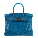 Blue crocodile leather handbag with Birkin design featuring gold hardware and structured silhouette