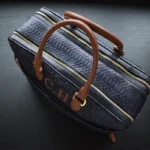 Blue python briefcase with cognac leather handles and gold hardware on dark surface