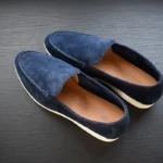 حذاء لوفر أزرق من جلد الغزال مصنوع يدويًا من جلد الغزال الكحلي ونعل أبيض على سطح خشبي