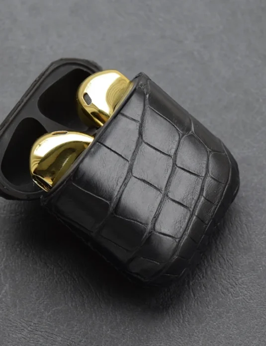Schwarze AirPods-Hülle aus Krokodilleder mit markantem Schuppenmuster und goldenen Akzenten