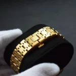 金色苹果手表表带，采用互锁拼图图案链节和折叠式表扣