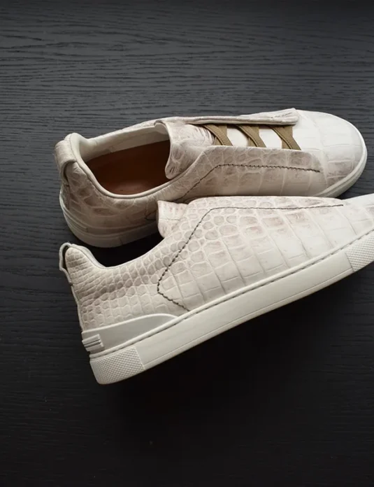 White crocodile leather sneakers showing detailed scale pattern and construction details