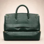 Dark green crocodile-embossed leather handbag with two top handles and a detachable bottom pouch.