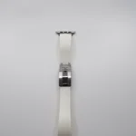 سوار ساعة أبل أبيض اللون، مزود بأجزاء معدنية فضية اللون ومشبك قابل للطي، على خلفية بيضاء
